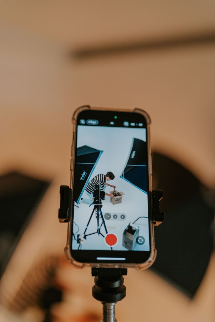 Close-up of a smartphone filming an unboxing in a modern studio setting.