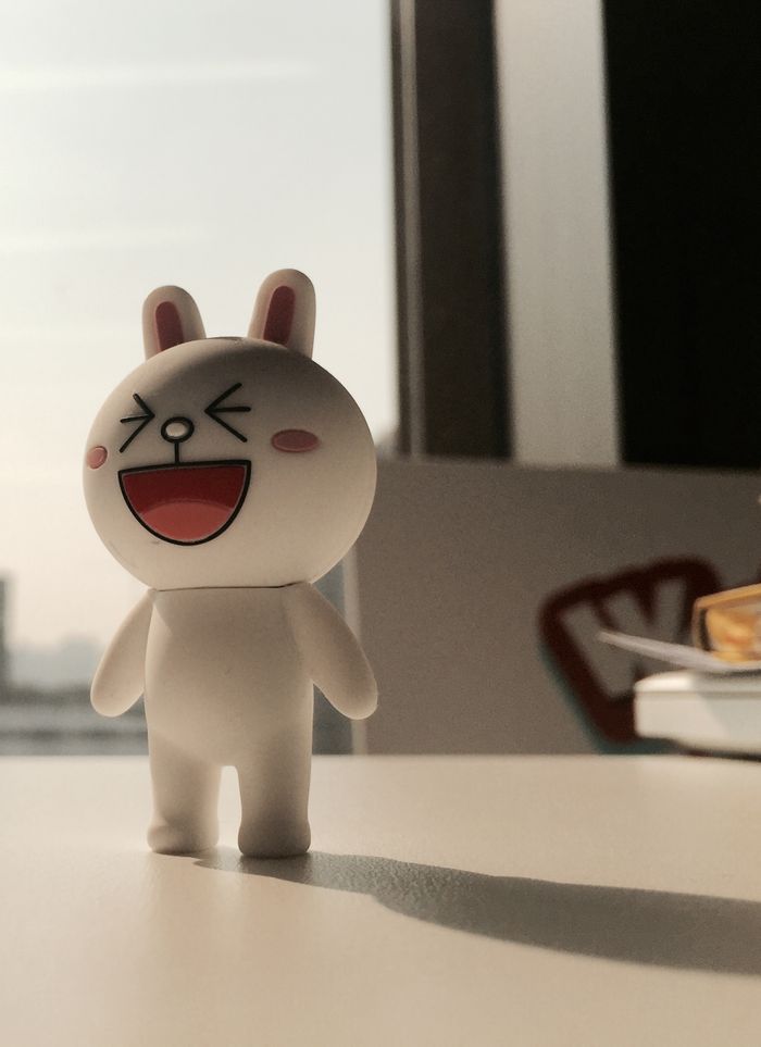 A playful bunny figurine standing on a table with morning light streaming through a window.