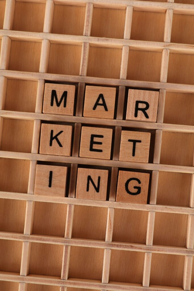 Wooden letter tiles arranged to spell 'marketing' on a wooden grid, depicting business strategy.